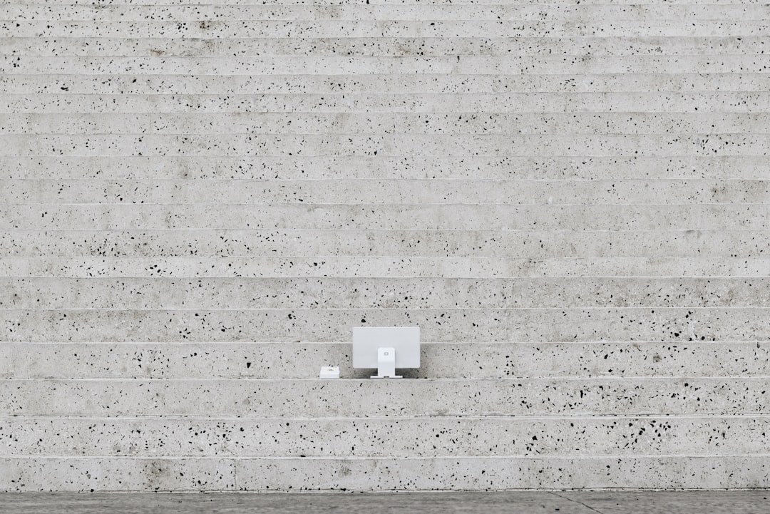 The SumUp POS Lite is placed on the steps of the Pyramid of Tirana, creating a striking contrast between modern payment technology and the iconic concrete architecture. The minimalistic design of the device stands out against the raw, textured stone, blending innovation with history in this unique setting.