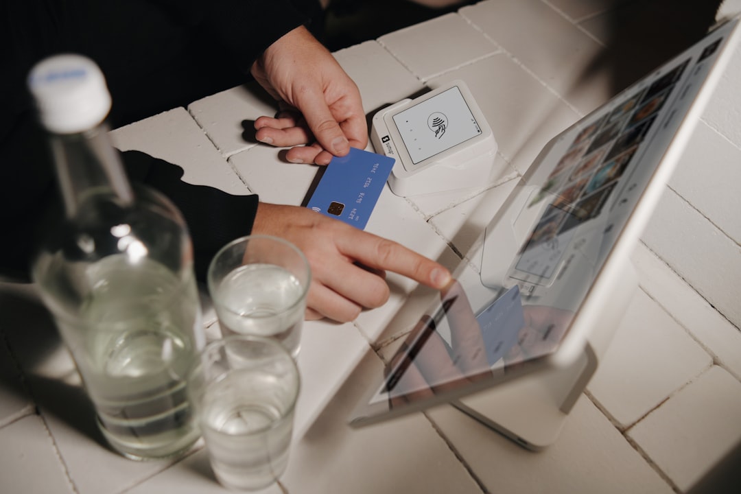 A customer making a contactless payment with a blue credit card on a SumUp point of sale system at a small business. The sleek setup with a tablet and SumUp card reader highlights the efficiency and modernity of digital transactions.